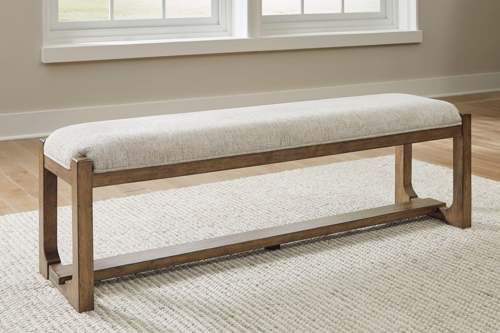 Front angle of Cabalynn 63-inch dining bench with oatmeal upholstery and light brown wood base