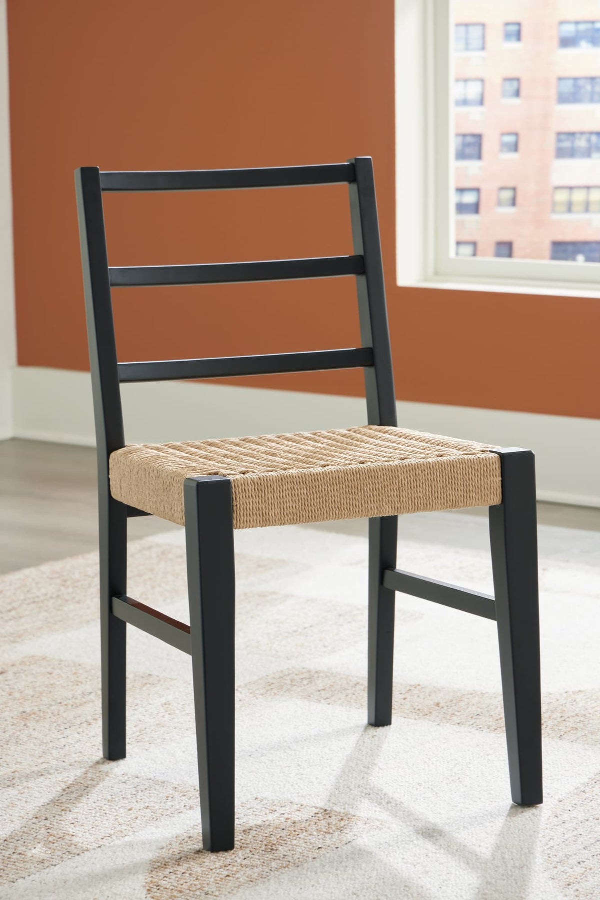 Isanti dining chair angled view showing light brown rattan seat and black wood frame