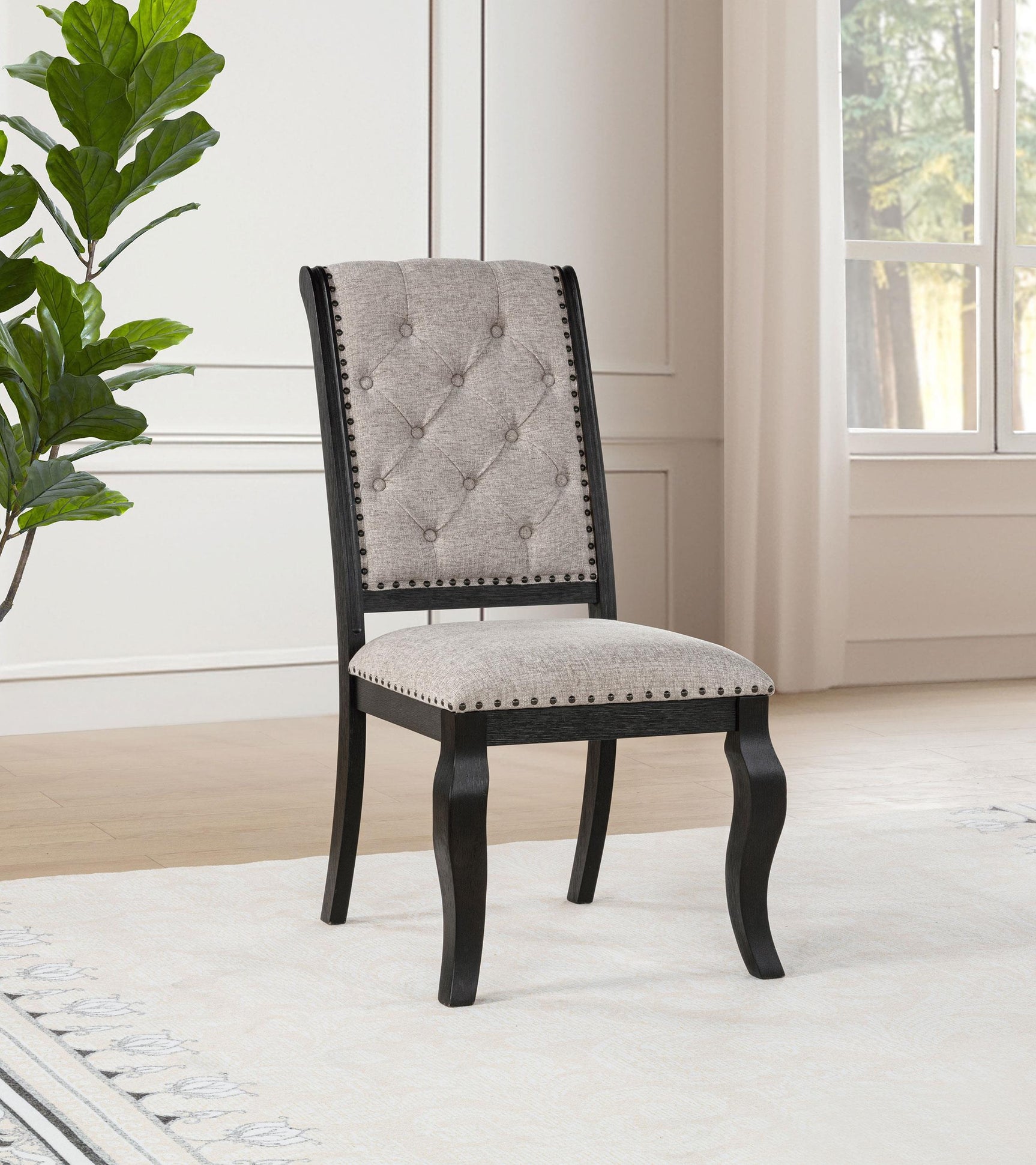 Side angle of Phelps upholstered dining chair showing distressed noir rubberwood legs