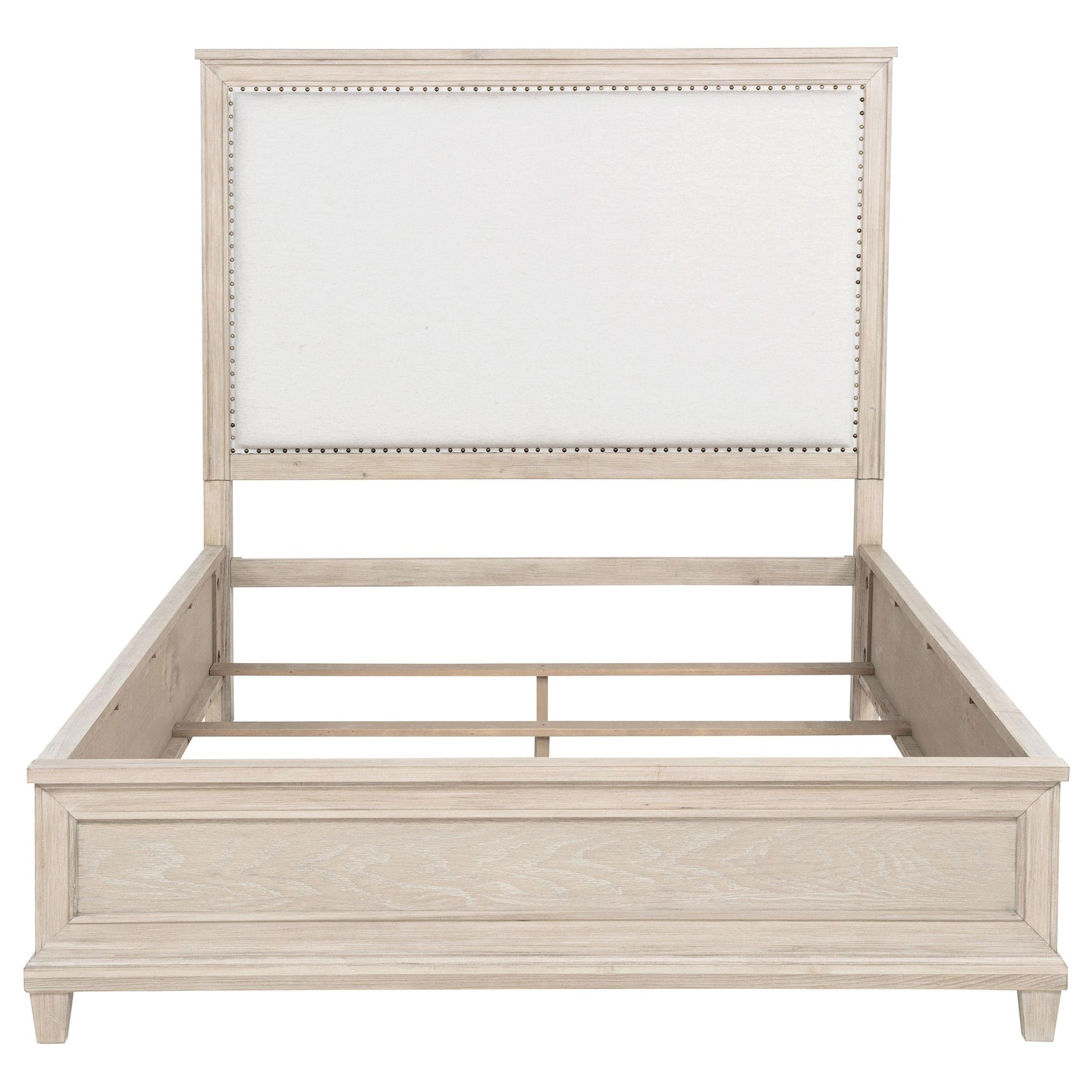 Close-up of washed oak frame and cream fabric headboard with nailhead trim