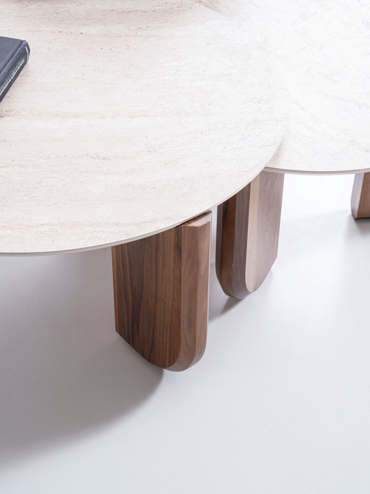 Close-up of walnut table edge and travertine top on Olena set
