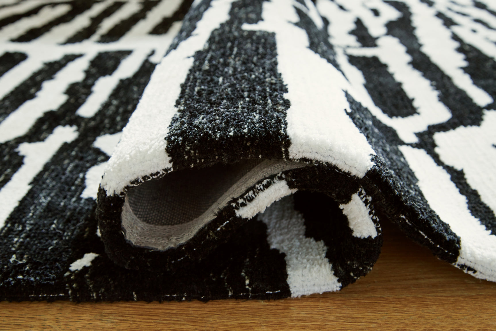 Rolled Bramshaw Black Ivory Medium Rug showing thickness