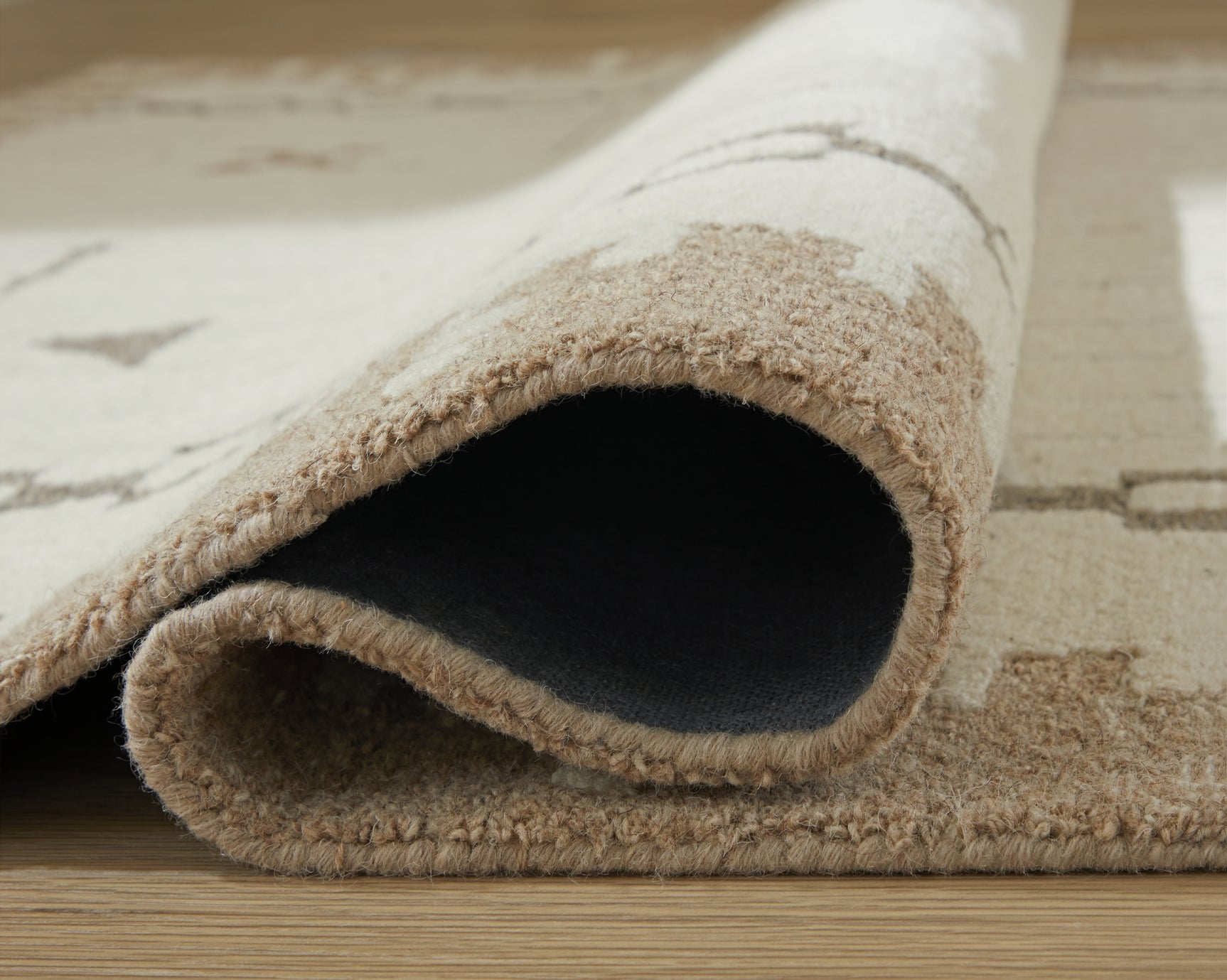 Rolled half of wool rug displaying thickness and backing
