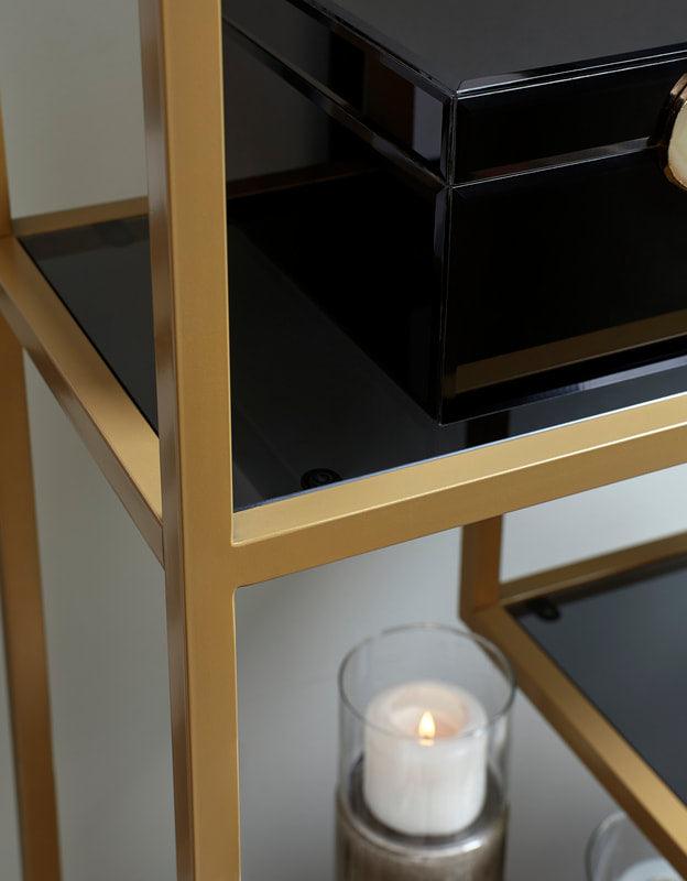Close-up of gold metal frame and gray tinted glass shelf on Frankwell bookcase