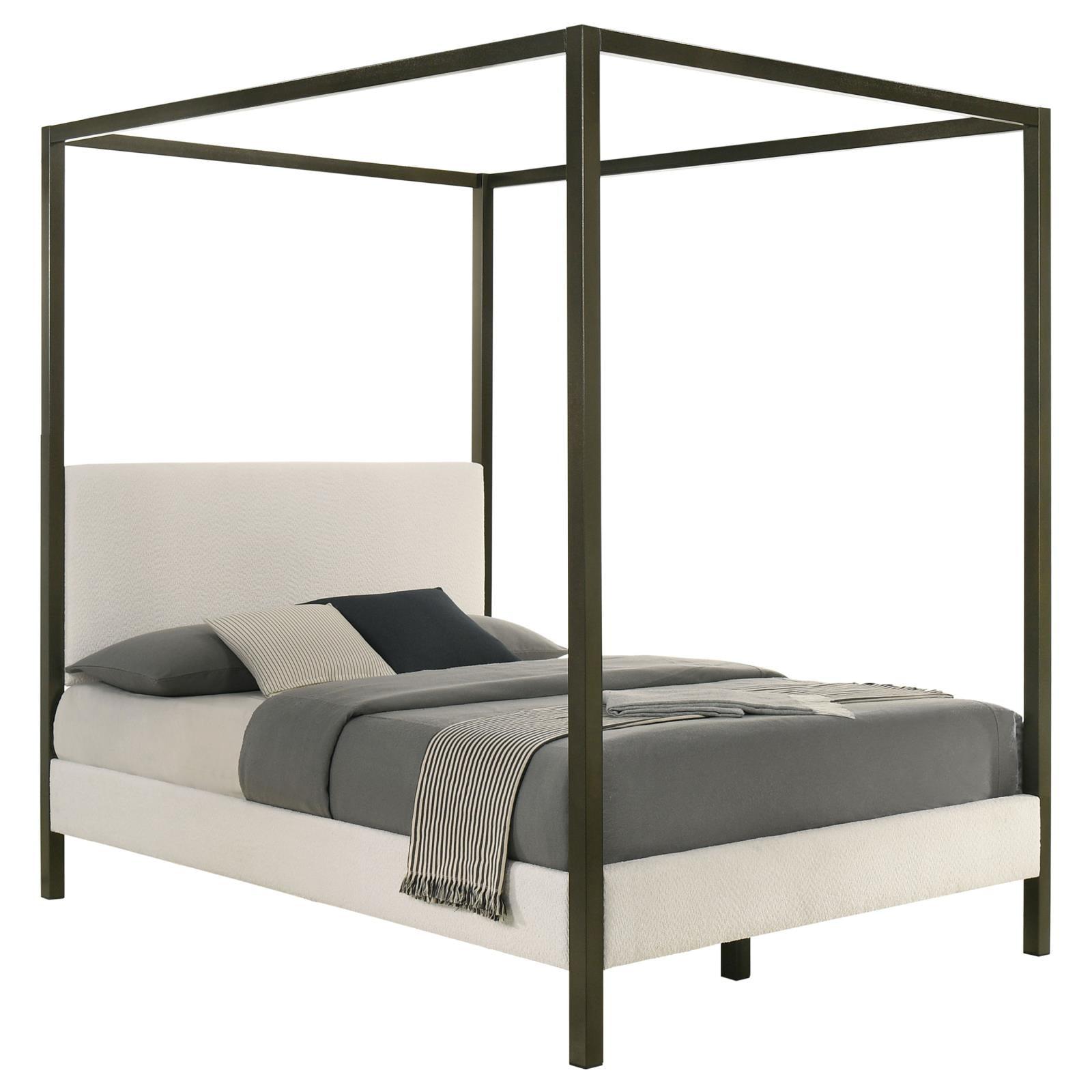 Close-up of padded headboard with vanilla upholstery and bronze posts