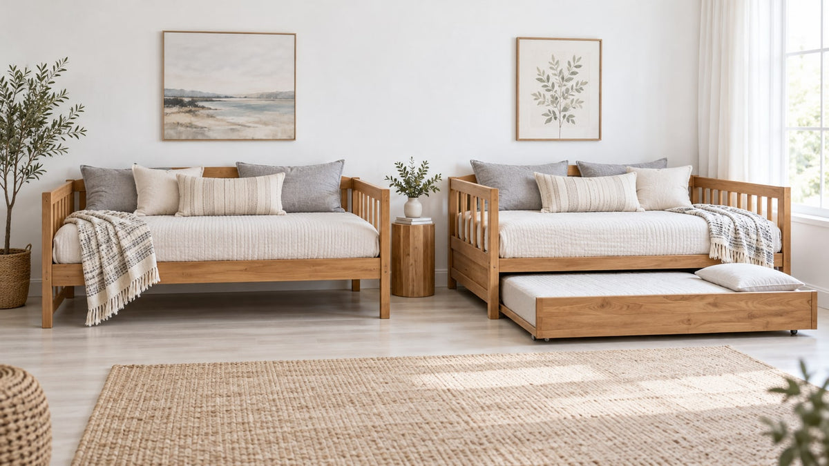 Neutral bedroom interior with a wooden daybed featuring an upholstered back and a pulled-out trundle mattress beneath, placed on a light area rug, bright natural light.