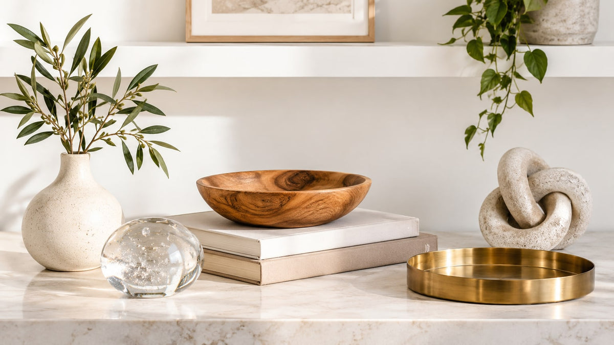 Stylish arrangement of mixed-material vases and decorative accessories on white surface in bright room