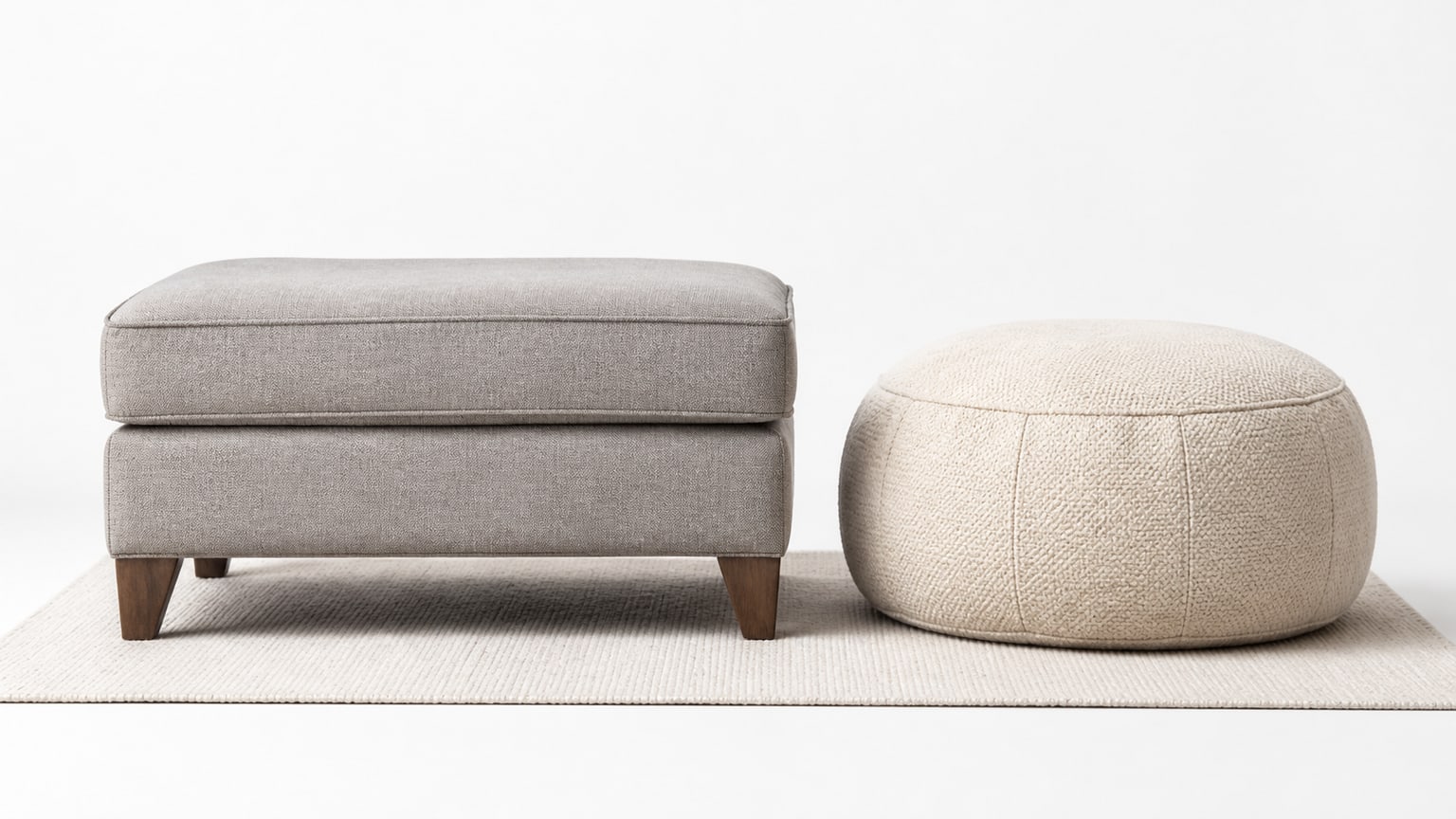Realistic furniture ecommerce photo showing a medium-sized upholstered ottoman and a smaller knitted pouf side by side on a clean white background.