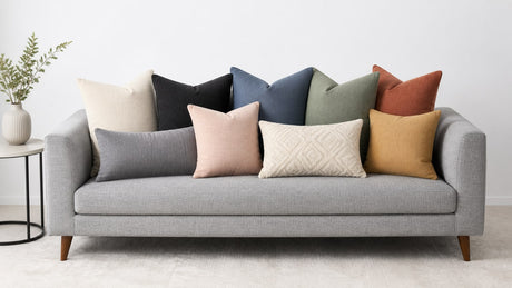 Modern gray sofa on white background with assorted throw pillows in cream, black, blue, green, rust, mustard, blush, and patterned designs