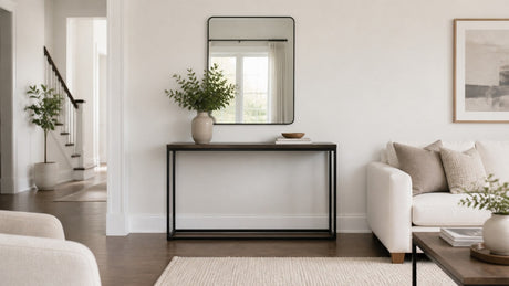 Medium wood tone console table styled with a table lamp and decorative greenery on a white background