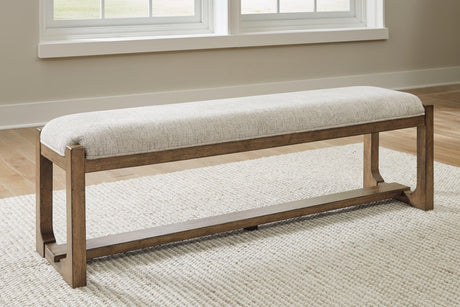 Front angle of Cabalynn 63-inch dining bench with oatmeal upholstery and light brown wood base