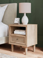 Front view of Cielden Two-Tone Nightstand showing light oak finish and beige cane drawer