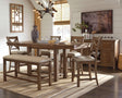 Moriville grayish brown counter height dining table with upholstered bar stools and bench, view from front angle