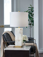 Linderfield white alabaster and goldtone table lamp illuminated on side table