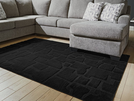 Gibbswell Black Washable 5' x 7' Area Rug laid flat in room