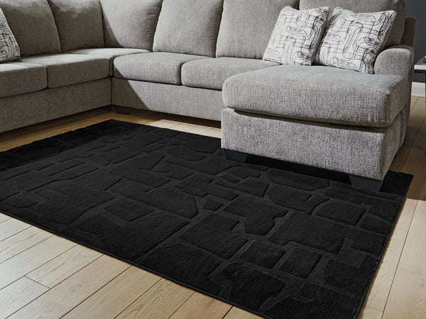 Gibbswell Black Washable 5' x 7' Area Rug laid flat in room