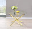Beckham round dining table with brass metal base and clear glass top, angled view