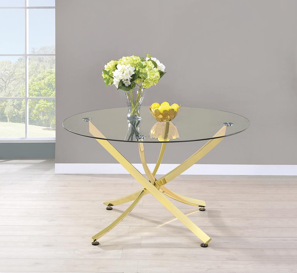 Beckham round dining table with brass metal base and clear glass top, angled view