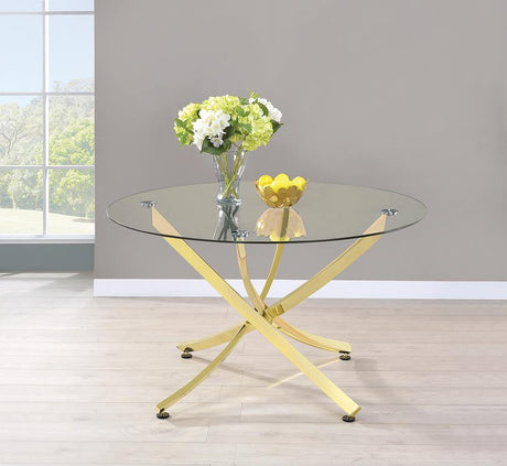 Beckham round dining table with brass metal base and clear glass top, angled view