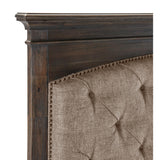 Close-up of tufted brown fabric headboard with nailhead details