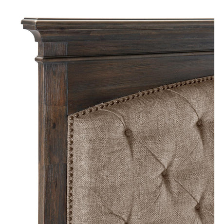 Close-up of tufted brown fabric headboard with nailhead details