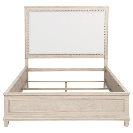 Close-up of washed oak frame and cream fabric headboard with nailhead trim
