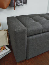 Close-up of tufted gray upholstery and wood legs