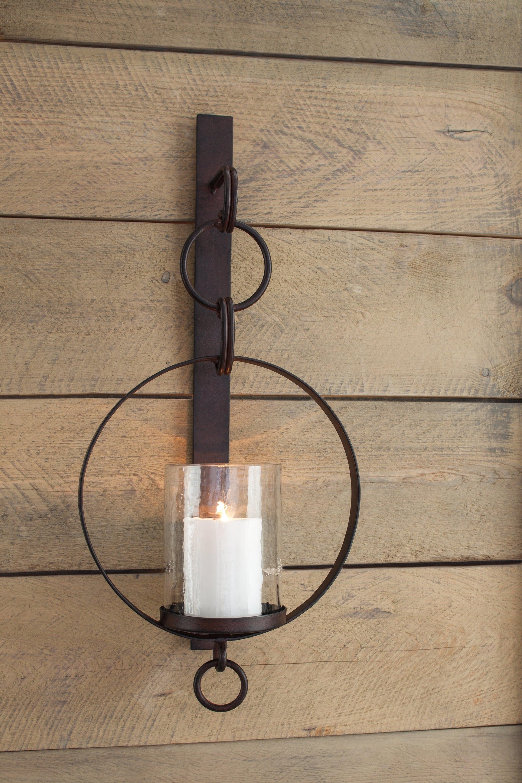 Ogaleesha Wall Sconce mounted on wall with pillar candle inside glass shade