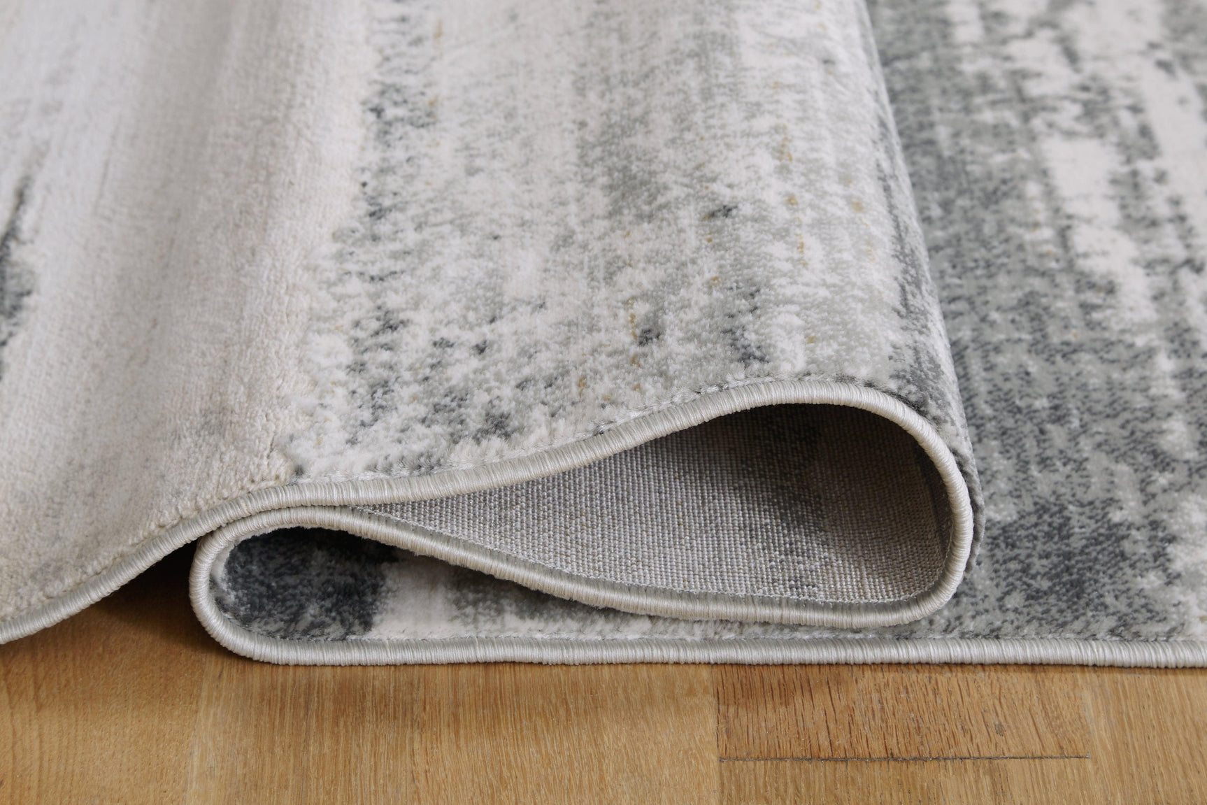 Rolled edge of Abanett Multi 7'10" x 10'2" rug showing thickness and backing