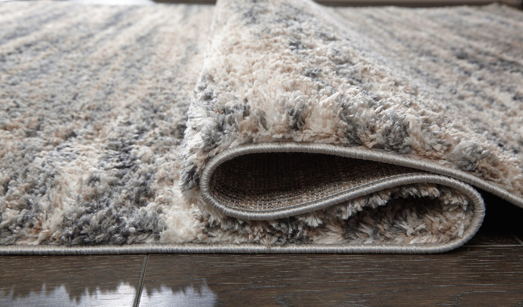 Rolled section of Gizela Ivory Beige Gray striped rug