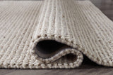 Rolled edge of Jossick cream taupe rug displaying fabric backing