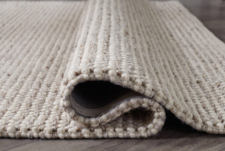 Rolled edge of Jossick cream taupe rug displaying fabric backing