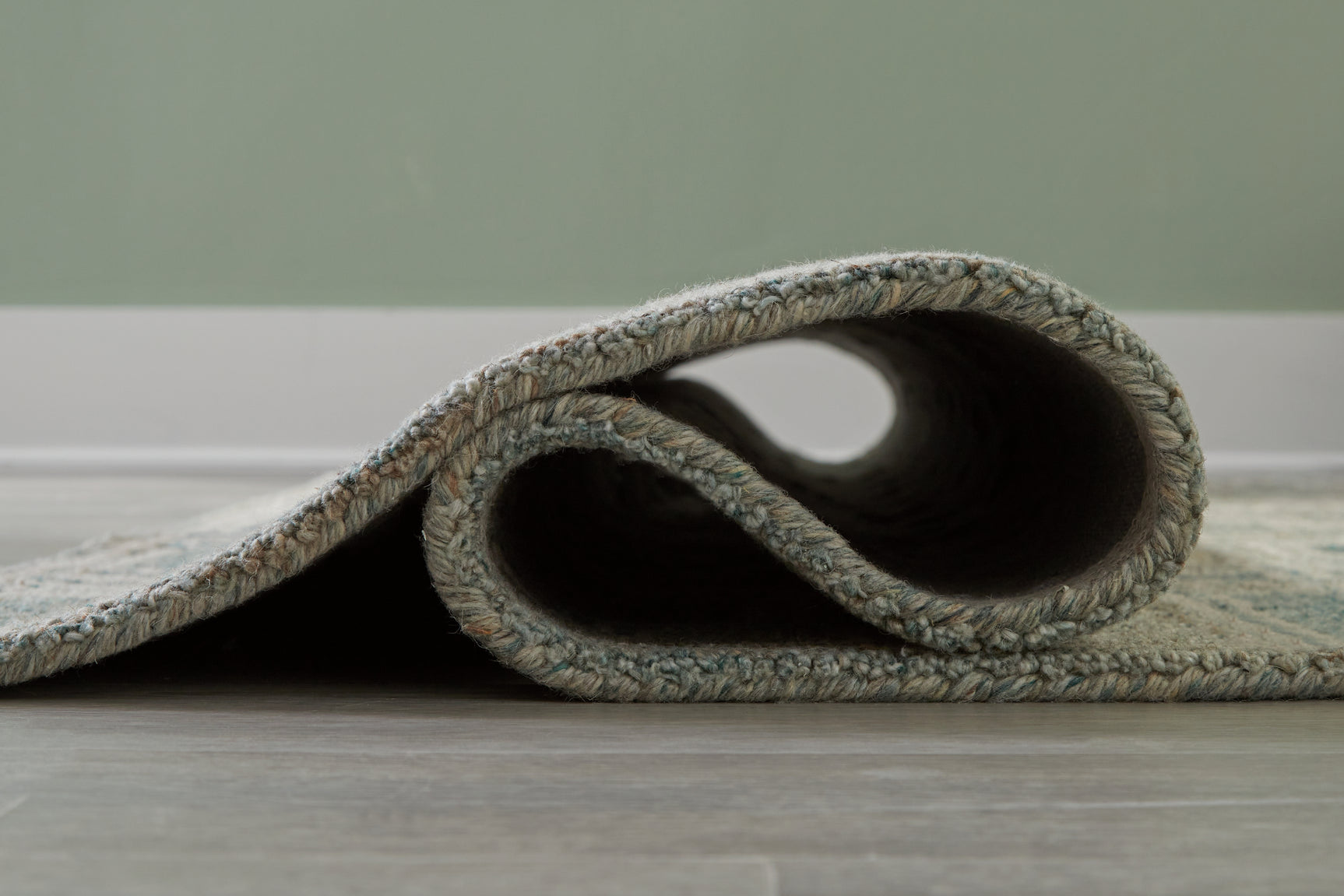 Rolled view of Jossland green ivory rug pattern