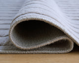 Worthley Gray area rug rolled showing backing texture
