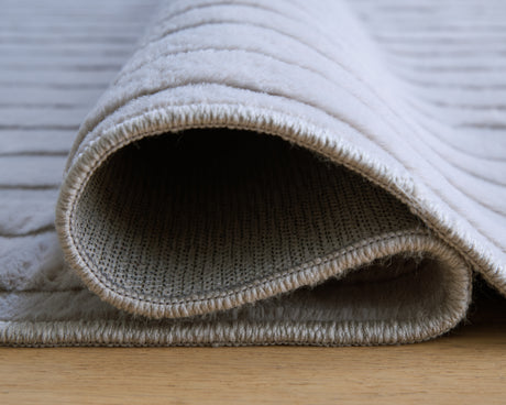 Worthley Gray area rug rolled showing backing texture