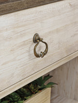 Detailed view of antiqued brass-tone hardware on Willowton TV stand