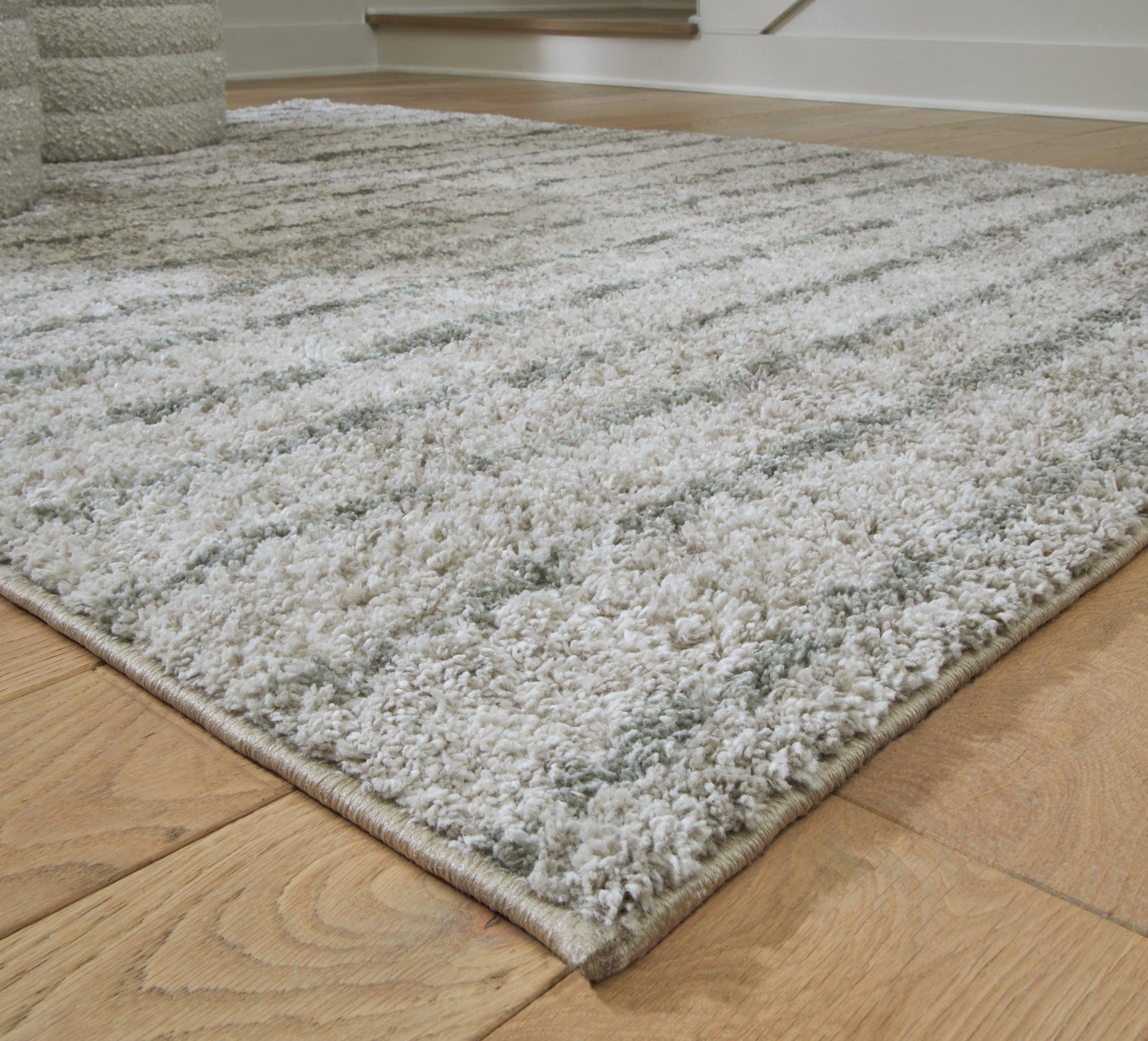 Side angle showing thickness of Laddway cream and green medium area rug