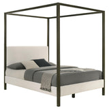 Close-up of padded headboard with vanilla upholstery and bronze posts