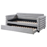 Grey upholstered twin daybed with trundle against white background