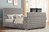Side angle showing gray velvet upholstery and footboard TV stand