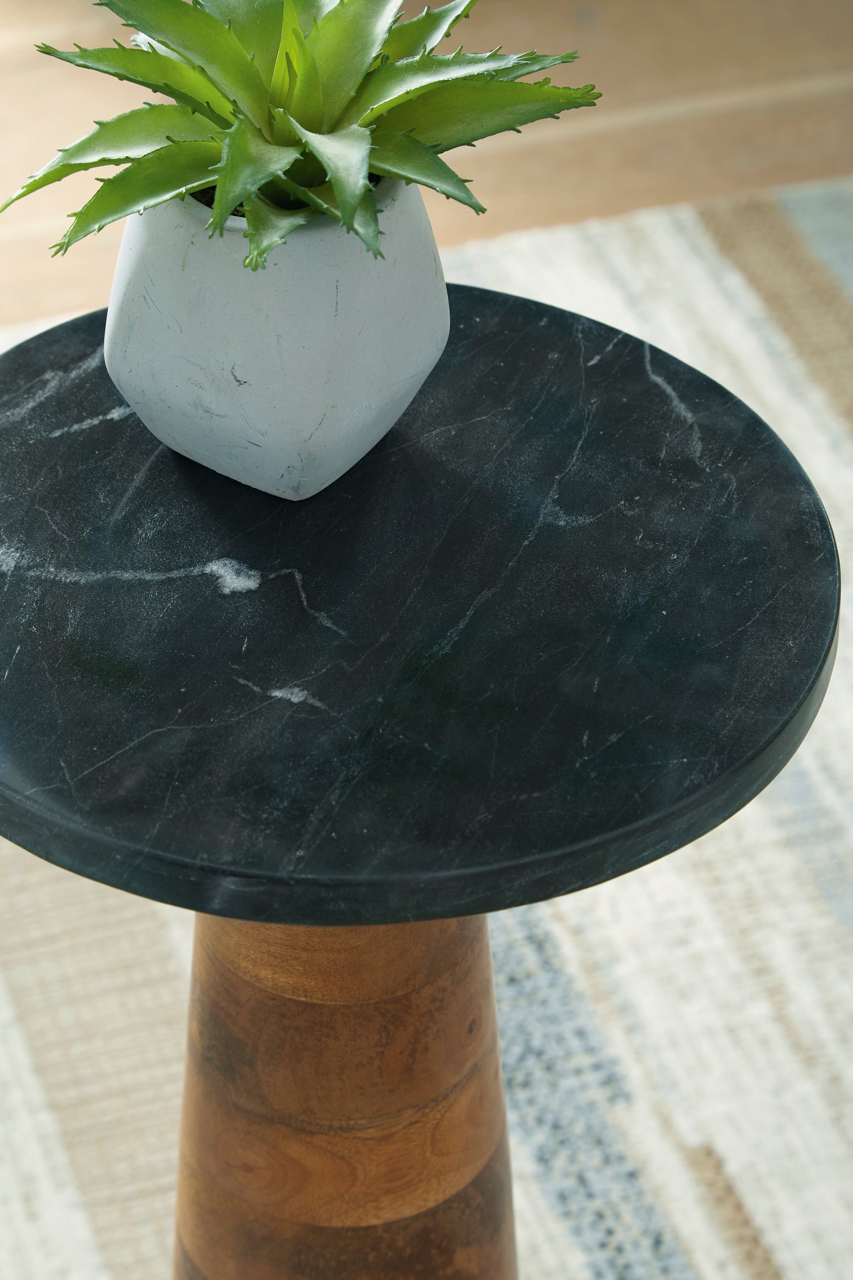 Quinndon accent table with medium brown wood base and black marble top on room setting