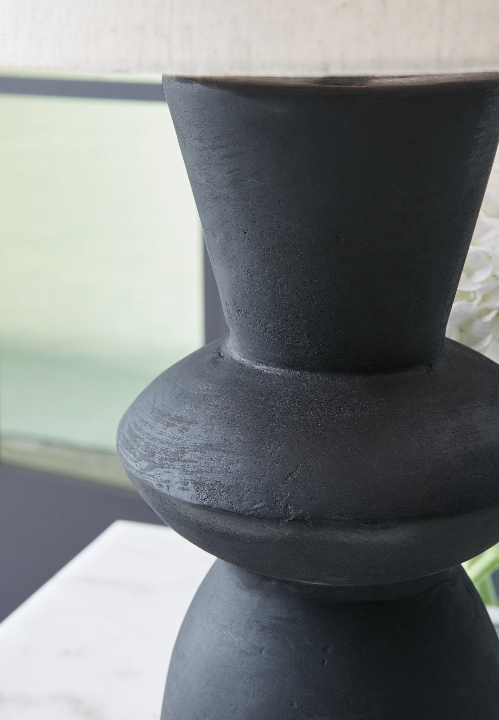 Close-up on distressed black base and fabric shade of Scarbot lamp